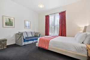 a bedroom with a bed and a couch and a window at Stunning newly renovated home in perfect location in Hobart