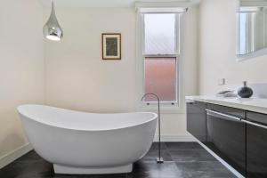a white bath tub in a bathroom with a sink at Stunning newly renovated home in perfect location in Hobart
