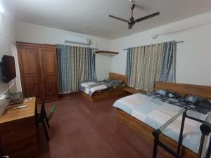 a bedroom with two beds and a tv in it at Ritu Homestay (The Second Wind) in Trivandrum