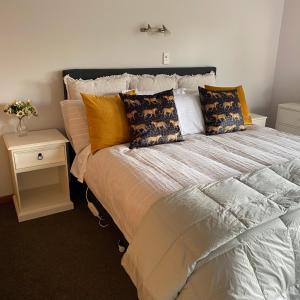 a bedroom with a bed with pillows and a night stand at Large, Comfy, Stylish Apartment in Havelock North