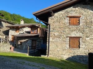 a stone building with wooden doors and a balcony at L'Oasi di Sodani1 in Sampeyre