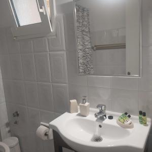 a white bathroom with a sink and a mirror at Studios Rania - Rania Studios & Apartments in Lassi