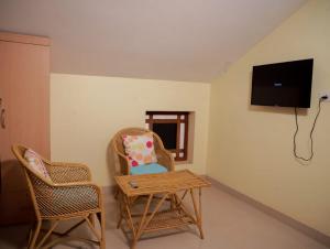 um quarto com duas cadeiras, uma mesa e uma televisão em Ritu Homestay (The Second Wind) em Trivandrum