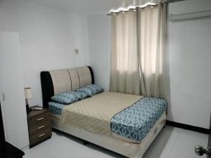 um pequeno quarto com uma cama e uma janela em Three-Bedroom Holiday Home - 4th Floor Stairs Only em Mactan