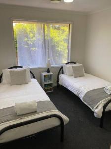 two beds in a room with a window at Open 4 bedroom home in Warrnambool