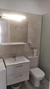 Baño blanco con aseo y lavamanos en AVRA-2 Apartments Potamos CORFU en Potamós