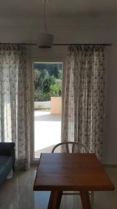 uma sala de estar com uma mesa de madeira e uma grande janela em AVRA-2 Apartments Potamos CORFU em Potamós