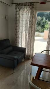 salon z kanapą, stołem i oknem w obiekcie AVRA-2 Apartments Potamos CORFU w mieście Potamós