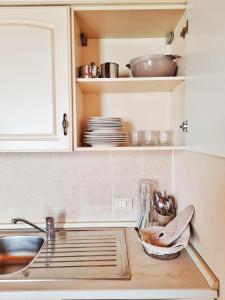 a kitchen with white cabinets and a sink and dishes at Agriturismo Ceolara in Sommacampagna