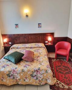 a bedroom with a bed and a red chair at Agriturismo Ceolara in Sommacampagna
