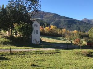 a white house in a field with mountains in the background at Gîte d'étape d'Aurouses in Die