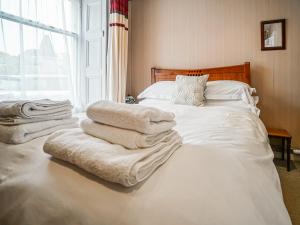 a bed with white sheets and towels on it at The Rennie Mackintosh Retreat in Comrie