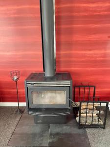 a stove sitting next to a red wall at Bungalow on Centre in Invercargill