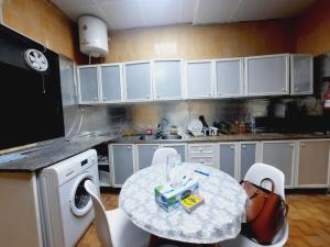 a kitchen with a table and white cabinets at Private Hall Room Bed Room and Washroom Room In Shared Apartment Flat 302-1 in Abu Dhabi