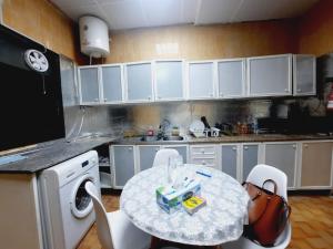 a kitchen with a table and white cabinets at Private Hall Room Bed Room and Washroom Room In Shared Apartment Flat 302-1 in Abu Dhabi +13 photos