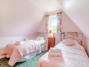 a attic bedroom with two beds and a window at Bryanstown Annexe in Woodbridge