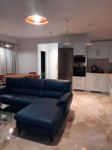 a living room with a blue couch and a kitchen at AVRA-3 Luxury Apartment in Potamós