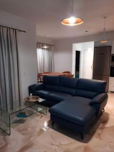 a living room with a blue couch and a glass table at AVRA-3 Luxury Apartment in Potamós