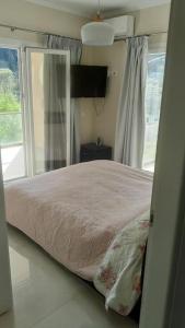 um quarto com uma cama, uma janela e uma televisão em AVRA-3 Luxury Apartment em Potamós
