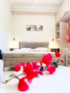 ツォウカラデスにあるStavros Apartmentsのベッドルーム1室(ベッド1台、テーブル上の赤い花付)