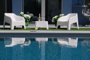 two white chairs and a table next to a swimming pool at Villa Karolina Luxury Pool Villa Desenzano del Garda in Desenzano del Garda +19 photos