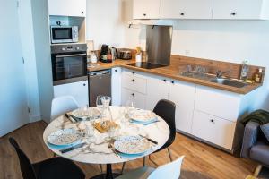 eine Küche mit einem Tisch mit Tellern und Gläsern darauf in der Unterkunft Joli T2 - Hennebont centre in Hennebont