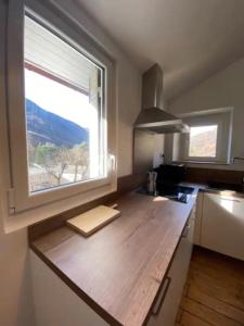 a kitchen with a wooden counter with a window at Le Chalet - Appartement 5 personnes avec parking in Savignac-les-Ormeaux