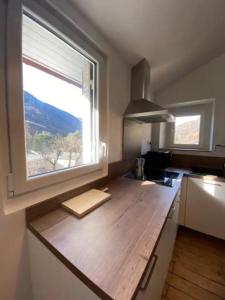 - une cuisine avec un comptoir en bois et une fenêtre dans l'établissement Le Chalet - Appartement 5 personnes avec parking, à Savignac-les-Ormeaux