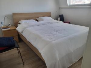 een groot wit bed in een slaapkamer met een stoel bij Beautiful spacious appartment at top location The Hague in Den Haag