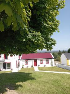 a white building with a red roof at Tiernan's Luxury Cottages in Newtown-Dillon