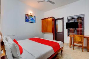 Dormitorio con cama, escritorio y TV en OYO Flagship 81056 Poptavern Heritage en Kovalam