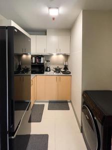 eine kleine Küche mit weißen Schränken und einem schwarzen Kühlschrank in der Unterkunft Amazing Unit and View in Uptown Parksuites BGC in Manila