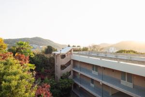 an apartment building with trees and mountains in the background at LOG in Onomichi