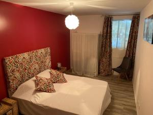 sypialnia z łóżkiem i czerwoną ścianą w obiekcie Gîte du Voyageur de la Maison Blanche 4p w mieście Saint-Yzans-de-Médoc