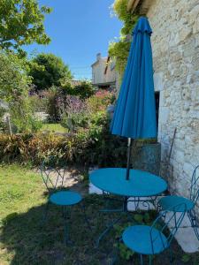 stół z niebieskim parasolem i dwoma krzesłami w obiekcie Gîte du Voyageur de la Maison Blanche 4p w mieście Saint-Yzans-de-Médoc