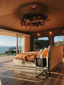 a bedroom with a bed and a view of the ocean at Drift Off Grid Luxury Eco Glamping in Tarakohe