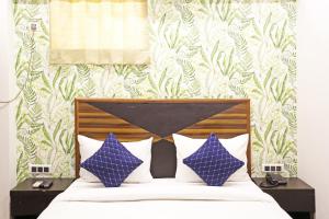 een slaapkamer met een bed met blauwe en witte kussens bij Hotel GL Suites Near Delhi Airport in New Delhi