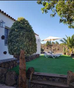 a garden with a bench and an umbrella at CASA RURAL FINCA LOS PAREDONES in El Paso