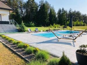 a patio with a table and chairs and a swimming pool at Saskia Dwór & Spa willa z podgrzewanym basenem in Podmacharce