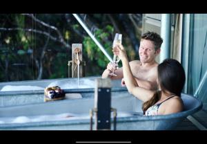 a man taking a picture of a woman in a bathtub at Drift Off Grid Luxury Eco Glamping in Tarakohe