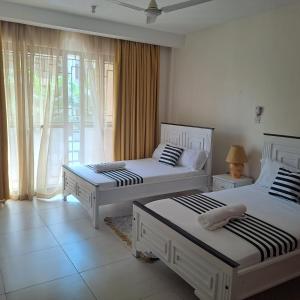 a bedroom with two beds and a window at Spacious three bedroom apartment with a pool in Mombasa
