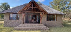 a small house with a thatched roof on the grass at Mothopo Game Lodge in Modimolle