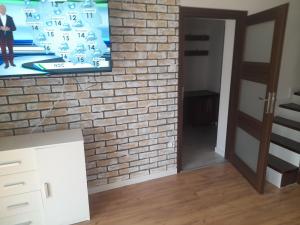 een kamer met een bakstenen muur en een tv bij ,,Domek Na Skarpie'' z Balią i basenem letnim in Sulęczyno