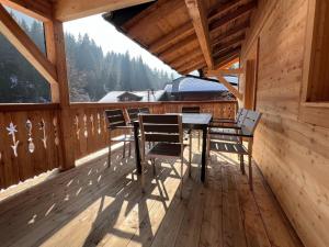a wooden deck with a table and chairs on it at ZE Mountain Lodge, Morgins in Morgins