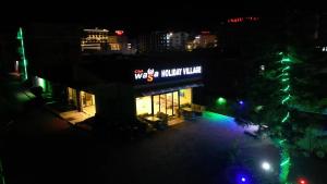 una vista de un edificio con un cartel por la noche en Club Wasa Holiday Village All Inclusive, en Toslak