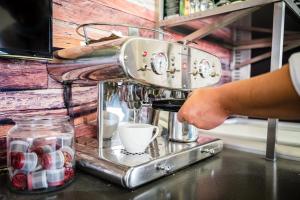 eine Person, die eine Kaffeemaschine auf einer Theke benutzt in der Unterkunft Marina Martinshafen - Beach life in Sassnitz