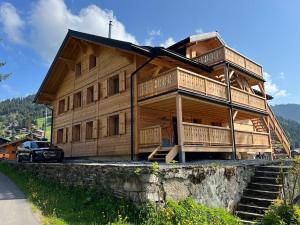 a large wooden house with a car parked in front of it at ZE Mountain Lodge, Morgins in Morgins