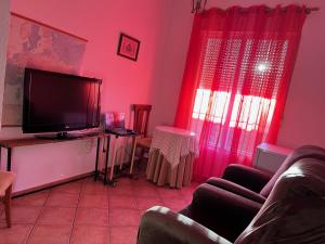 sala de estar con paredes de color rosa y TV de pantalla plana. en Habitación con baño Malva, en Lepe