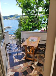 einen Tisch und Stühle auf einem Balkon mit Blick auf das Wasser in der Unterkunft Apartmani Anđela Kordić in Rab