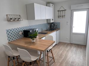 een keuken met een houten tafel en witte kasten bij Studio cosy avec terrasse, proche Chantiers et Airbus in Saint-Nazaire